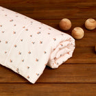 Ein aufgerolltes KraftKids Bettwäscheset Musselin Kirschen aus 100% Baumwolle mit Kirschmuster liegt auf Holz, neben fünf Holz-Kugeln - die perfekte Ergänzung für handgefertigte Bettwäsche und erholsamen Schlaf.