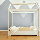 Das KraftKids Rausfallschutz aus Leimholz Wolke ist ein minimalistisches Kinderbett mit wolkenförmigem Kopfteil und Holzrahmen, hell gemustertem Bettzeug und kindersicherem Fallschutz vor einer grauen, berggemusterten Wand.