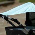 Nahaufnahme eines Kinderwagens mit dem Sonnensegel "weiße Pfeile auf Mint" von KraftKids, der leichten Schatten spendet. Der Hintergrund im Freien ist leicht verschwommen.