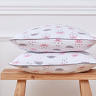 Zwei dekorative KraftKids Kissenbezüge, "Schnurrbart auf Blau" und "Unigrau", sind auf einem Holzhocker vor einer weiß getäfelten Wand gestapelt.