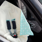 Über einem leeren Autositz ist eine KraftKids "Decke für Babyschale Winter weiße Pfeile auf Blau" drapiert, mit sichtbaren schwarzen Gurtbändern und einer roten Schnalle.