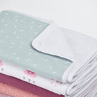 Neben der KraftKids Wickelunterlage Musselin mint Pusteblumen aus mintgrünem Musselin mit Pusteblumen und fröhlichen Motiven liegen weiche, pastellfarbene Babydecken ordentlich gestapelt.