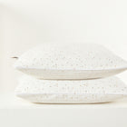 Zwei Kissen mit dem Kissenbezug Musselin goldene Punkte auf Weiß von KraftKids setzen einen stilvollen Akzent vor schlichtem, weißem Hintergrund und ergänzen perfekt Ihre Bettwäschekollektion.