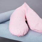 Das KraftKids qualitäts Stillkissen Streifen rosa mit ergonomischem Design ruht auf einer hellblau gepolsterten Bank mit Holzbeinen vor einem schlichten grauen Hintergrund.