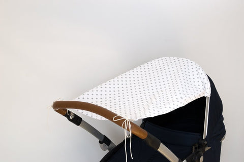 Der KraftKids Sonnensegel graue Punkte auf Weiss schützt Ihr Baby vor der Sonne mit seinem atmungsaktiven weißen Baumwollverdeck mit grauen Punkten, das sich leicht am Kinderwagengriff befestigen lässt und vor einem schlichten, hellen Hintergrund abgebildet ist.