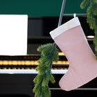 Die KraftKids Weihnachtssocke Doppelkrepp Rosa hängt an einer dekorierten Leiter mit grüner Tannengirlande vor einem Klavier mit Noten auf dem Ständer.