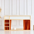 Ein minimalistisches Kinderhochbett mit einem Rahmen aus Naturholz, weißen Paneelen und KraftKids Hochbettvorhänge Set 2+1 Doppelkrepp in Rot Herbstrot für das Kura Bett steht vor einer weiß getäfelten Wand. In der Nähe stehen eine geflochtene Vase mit Pampasgras und zwei Holzhocker.