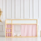 Ein minimalistisches Spielbett mit hellem Holzrahmen zeigt das KraftKids Hochbettvorhänge Set 2+1 Musselin goldene Punkte auf Rosa für Kura Bett in einem hellen Raum mit weiß getäfelten Wänden, dazu eine geflochtene Pampasgrasvase und zwei Holzhocker in der Nähe.