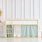 In einem minimalistischen Kinderzimmer steht ein IKEA Kura Hochbett mit hellem Holzrahmen und mintfarbenen KraftKids Hochbettvorhängen. Eine Weidenvase mit Pampasgras und zwei Holzklötze stehen auf dem weißen Boden daneben.